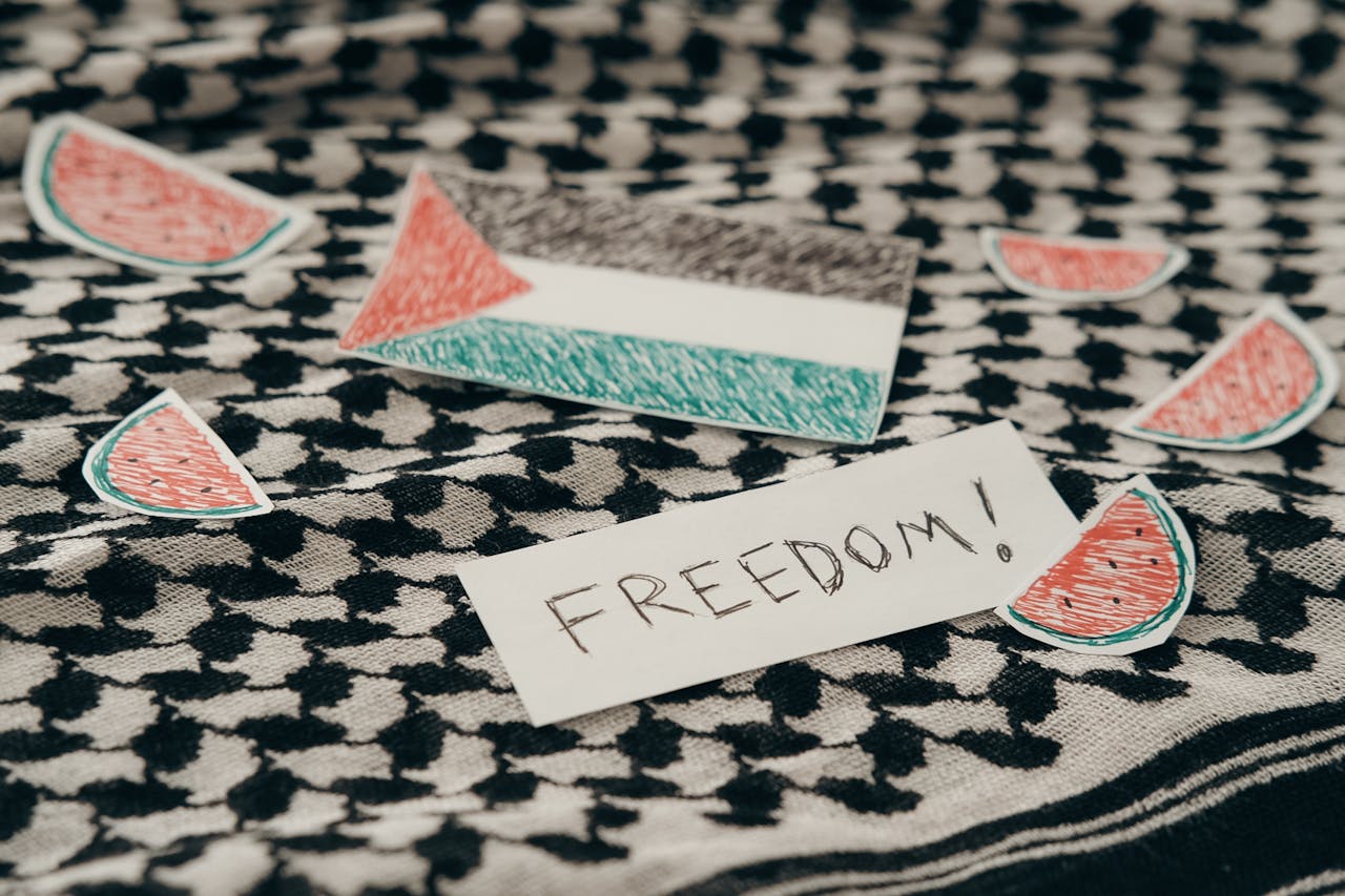 Palestinian flag and freedom note on keffiyeh surrounded by watermelon symbols.